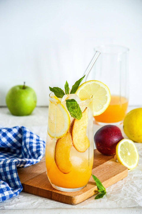 Eistee frisch zubereitet auf einem Holztablett, daneben liegt frisches Obst